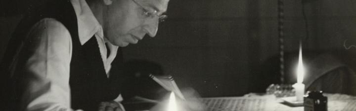 Aaron Copland writing music by candlelight. Photo by Victor Kraft.