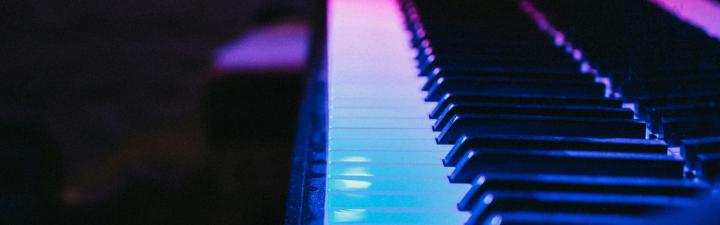 Piano keys under blue and magenta lights.