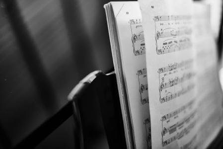 A grayscale close up of sheet music on a piano music desk.