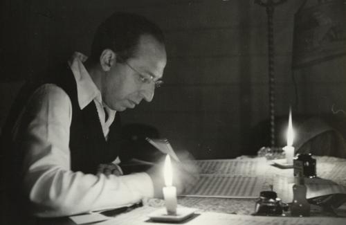 Aaron Copland writing music by candlelight. Photo by Victor Kraft.
