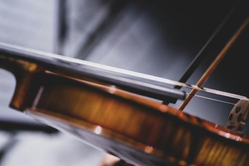 Close up of a violin being played against a black and gray abstract background.